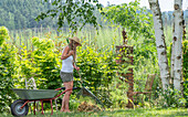 Frau recht Blätter und Gras im Garten