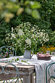 Gedeckter Tisch mit Strauß aus wilde Möhre (Daucus Carota) und Berufskraut im Garten