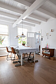 Bright dining room with wooden table, chairs and white-painted wooden beamed ceiling