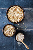Whole and ground rolled oats in bowls with wooden spoon
