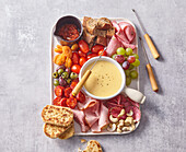 Cheese fondue with vegetables, salami, mortadella and bread
