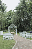 Outdoor ceremony area with white gazebo and chairs in the garden