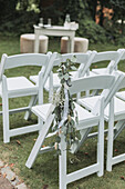 Weiße Gartenstühle dekoriert mit Eukalyptuszweigen