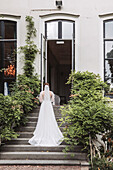 Bride in white dress climbs stone steps of historic building