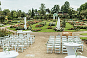 Outdoor wedding ceremony in rose garden with white seating