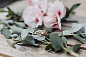 Engagement ring surrounded by eucalyptus branches and pink flowers