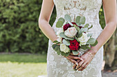Braut mit Hochzeitsstrauß aus roten und weißen Rosen und Eukalyptuszweigen