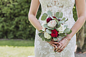 Bride with wedding bouquet of red and white roses and eucalyptus branches