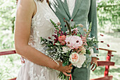 Bride and groom holding wedding bouquet with roses and eucalyptus