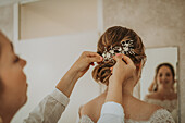 Woman puts hair jewelry into the updo of a bride