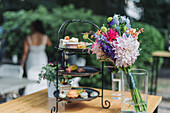 Three-tier etagere with pastries and chocolates, colorful bouquet of flowers in glass