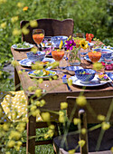 Set wooden table in the garden with colourful summer crockery and fresh drinks