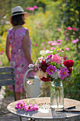 Gartentisch mit Blumenstrauß aus Dahlien (Dahlia), Rosen (Rosa), Herbstanemonen (Anemone Hupehensis) und wilde Möhre