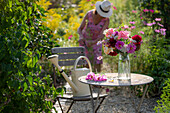 Garden seating area with bouquet of dahlias (Dahlia), roses (Rosa), autumn anemones (Anemone Hupehensis) and wild carrot