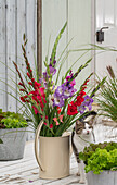 Colorful bouquet of gladioli (Gladiolus) in watering can on the patio