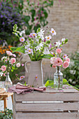 Bouquet and arrangement of funkia (Hosta), roses, autumn anemone (Anemone Hupehensis) in vases on a wooden crate