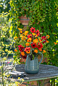 Bouquet of marigolds (Calendula) and dahlias (Dahlia) in a stone jug on the terrace