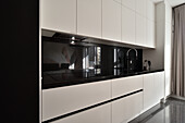 Modern kitchen unit with white fronts and black worktop