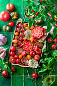 Different types of tomatoes with garlic and basil on a baking tray