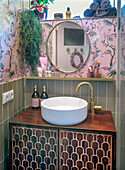 Small bathroom with pink wallpaper and golden fittings