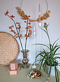 Autumnal decoration with rosehip branches, candles and houseplant