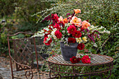 Herbstlicher Strauß aus Dahlien (Dahlia), Myrtenaster, Rosen, orientalischer Knöterich, Gartenfuchsschwanz (Amaranthus caudatus) auf Gartentisch