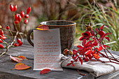 Note with handwritten poem about autumn leaves, with linen napkin, cup and rose hips, still life