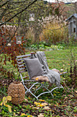 Seat in autumn garden with candle lanterns hanging in a tree