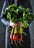 Man holding fresh beetroot with leaves