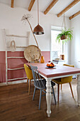 Dining area with wooden table, yellow chairs and hanging lamp under beamed ceiling