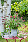 Bouquet of flowers with incarnate clover (Trifolium incarnatum) in a clay jug on a garden table