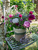 Bunter Strauß aus Pfingstrosen (Paeonia), Scheinwaldmeister, Skabiose, Wollziest, Katzenminze, Giersch und Zierlauch in Vase auf Gartenstuhl