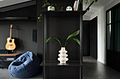 Modern flat in black with sculptural vase and green plant