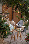 Weihnachtlich rustikal geschmückte Terrasse mit Sitzplatz vor Thuje und Christbaum mit Anhängern