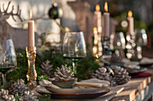 Weihnachtlich festlich gedeckter Tisch, Kiefernzapfen, Tannenzweige, Kerzenständer, Christbaumkugel