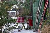 Sitzplatz im winterlichen Garten vor Hütte mit alten Skiern und Kiefer