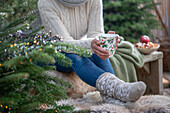 Frau mit weihnachtlicher Tasse und selbstgestrickten Socken 