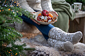 Frau hält weihnachtlichen Teller mit Zimtsternen, Äpfeln und Mandarinen