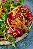 Smoked beef carpaccio with wild herbs, flowers and parmesan crisps