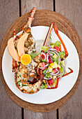 Grilled lobster with fruit salad on a white plate