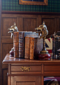 Antique books with bookends in the shape of dog heads and typewriter on wooden desk