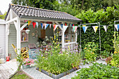 Gazebo with bunting, surrounded by plants and flowerbeds