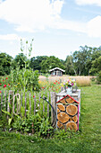 Garden with flower bed, insect hotel and summer meadow in the background