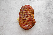 Whole piece of prosciutto in a net, air-dried ham