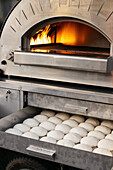 Dough pieces for pizza are stored under the pizza oven