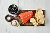 Raw salmon fillet with ciabatta and olives on a board