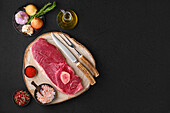 Raw beef steak on wooden board with spices and oil