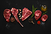 Various raw beef steaks with spices and olive oil