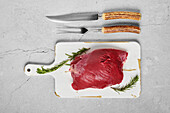 Raw beef from the shoulder with rosemary on a chopping board