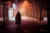 Young woman walking through city at night